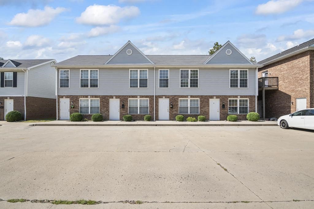 an empty parking lot in front of a brick apartment building