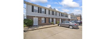 a row of apartment buildings with cars parked in front of them