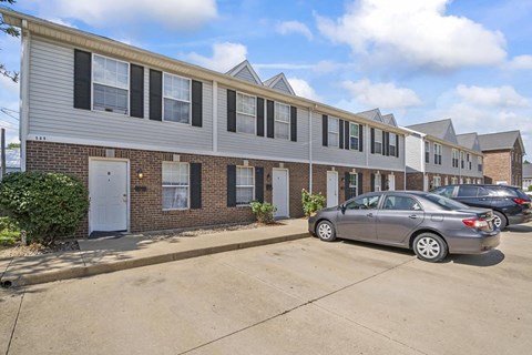 a row of apartment buildings with cars parked in front of them