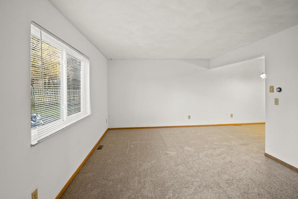 an empty room with a large window and carpet