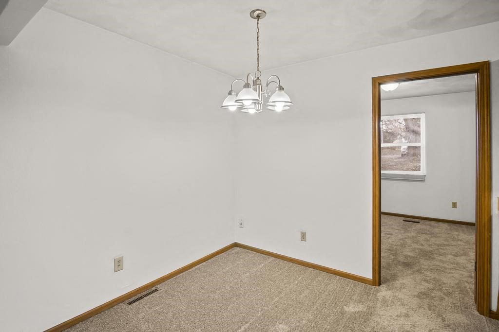 the living room and dining room of an empty house with a mirror
