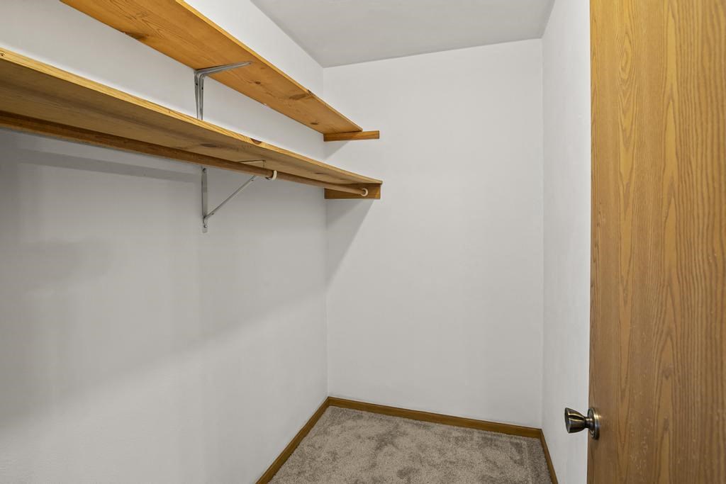 a walk in closet in a white room with a wooden door