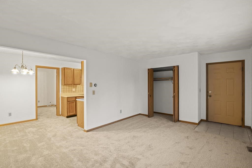 an empty living room with a door to a kitchen
