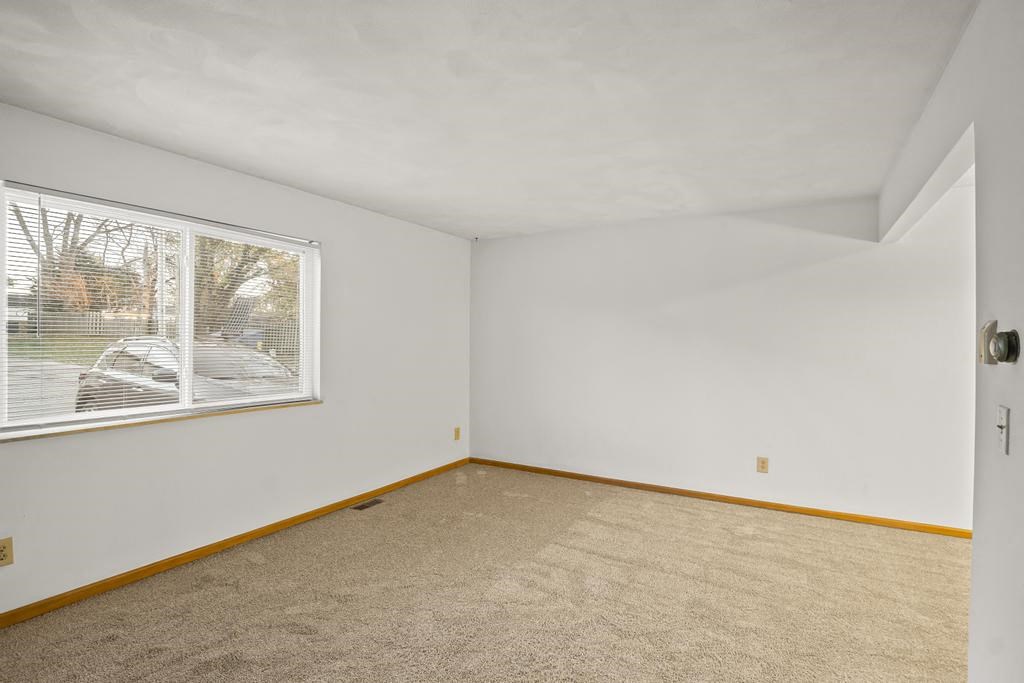 an empty room with a large window and carpet