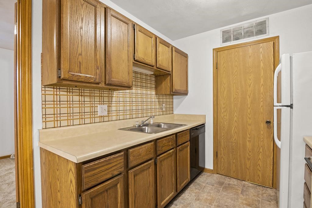 a kitchen with wooden cabinets and a sink and a refrigerator