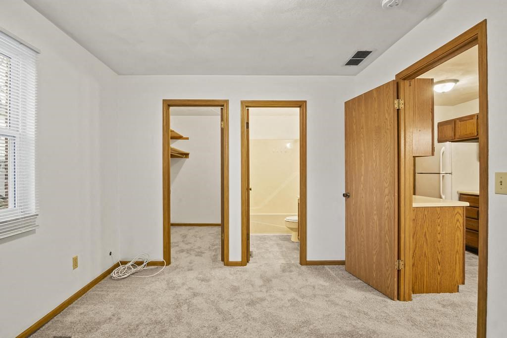 a bedroom with a door to a bathroom and a closet