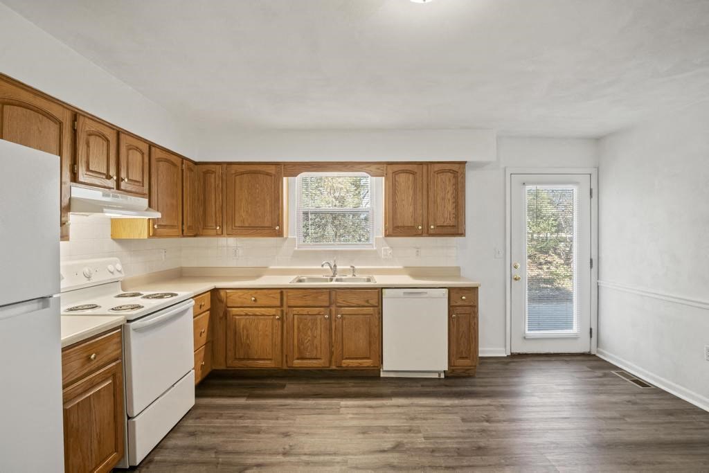 an empty kitchen with wooden cabinets and white appliances