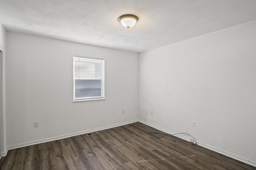 the living room of an empty home with white walls and a window