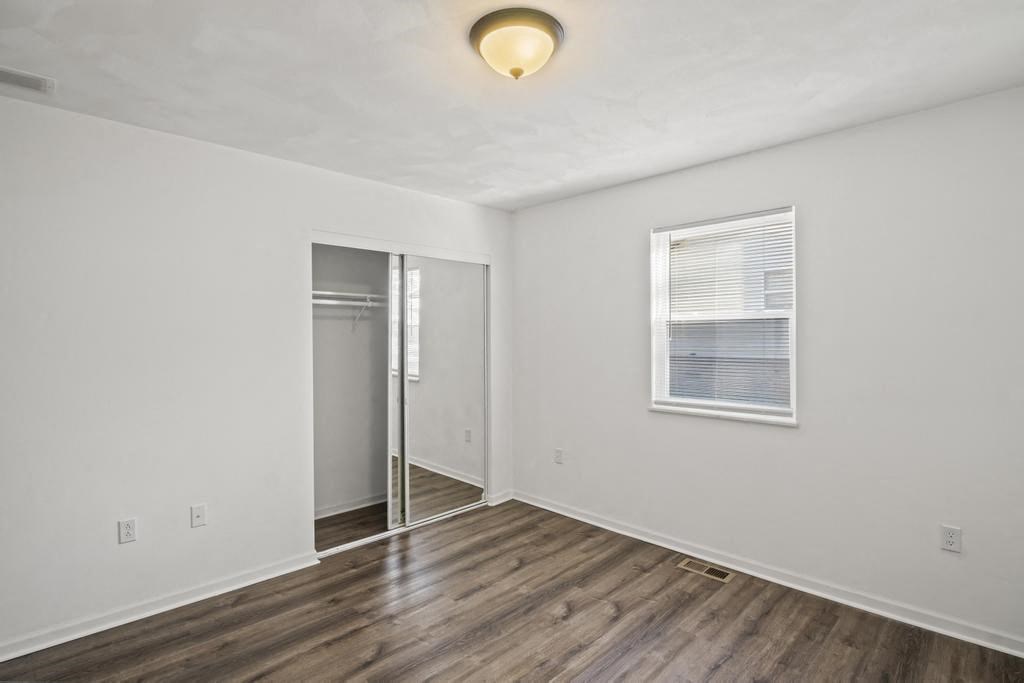 an empty room with white walls and a window and wood floors