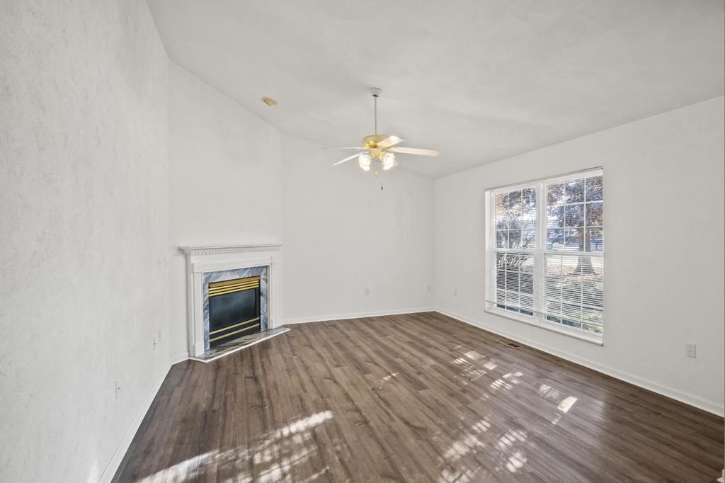 an empty living room with a fireplace and a ceiling fan