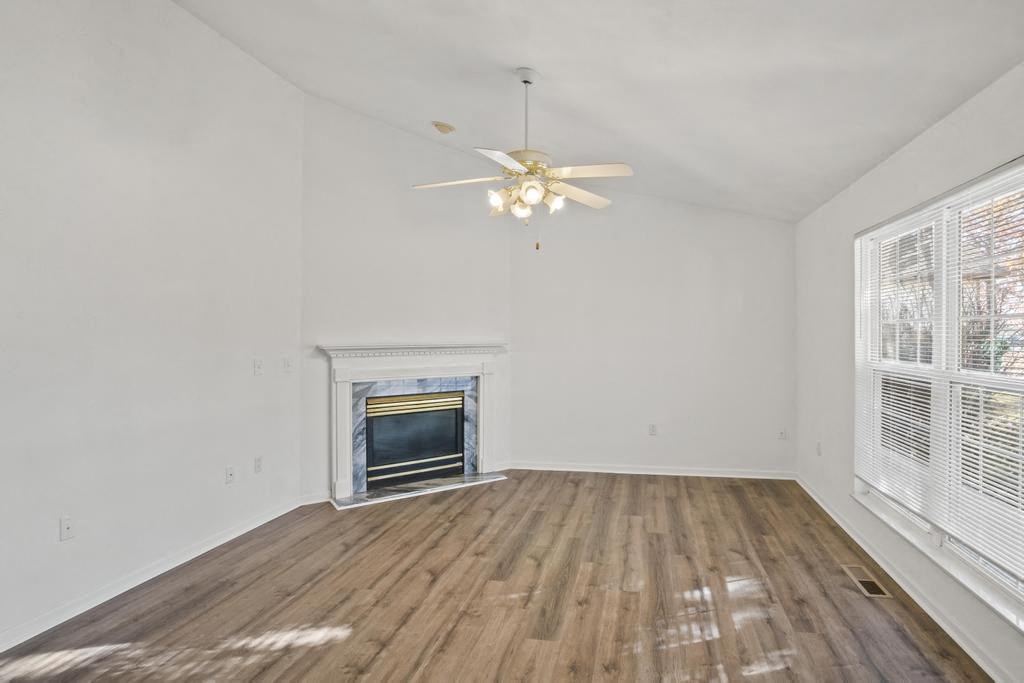 an empty living room with a fireplace and a ceiling fan