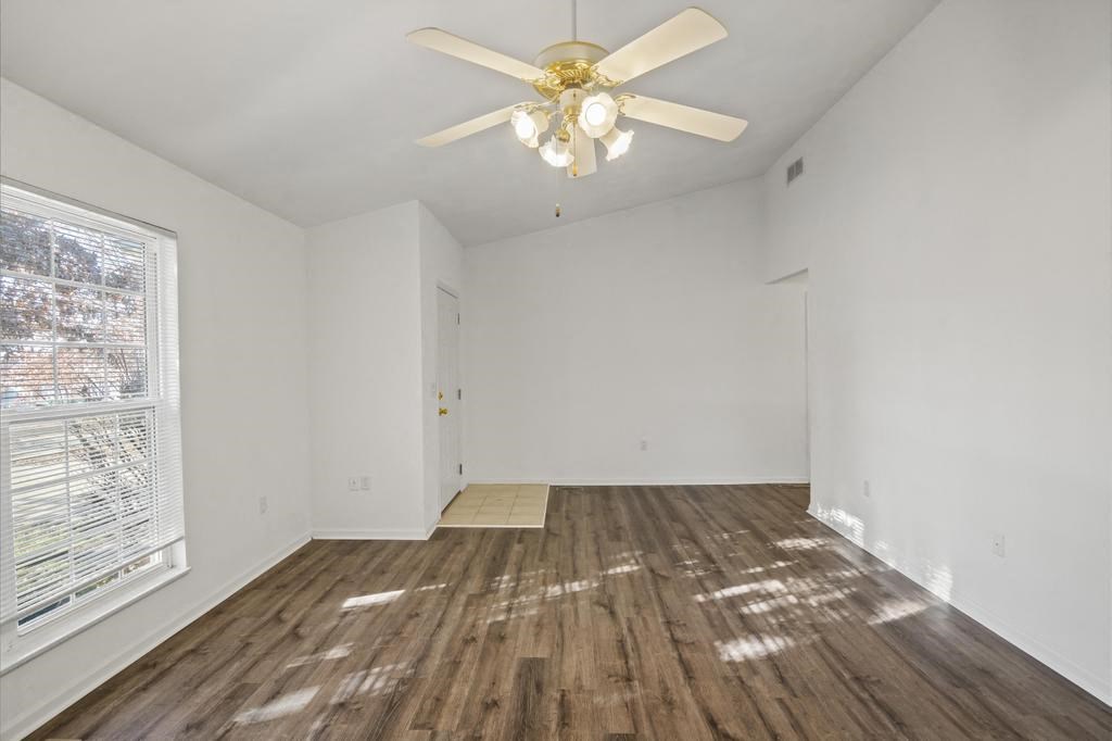 an empty living room with white walls and a ceiling fan