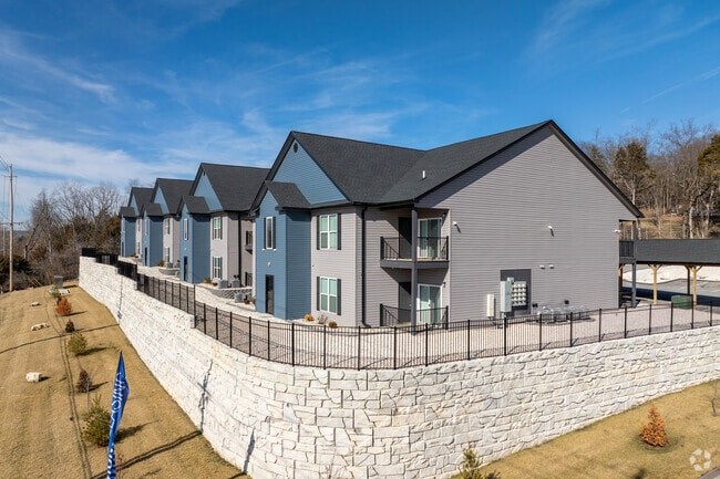A row of houses with grey roofs and a stone wall in front.