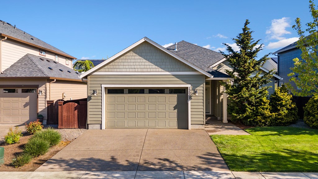 A house with a grey garage door is in front of a green lawn.