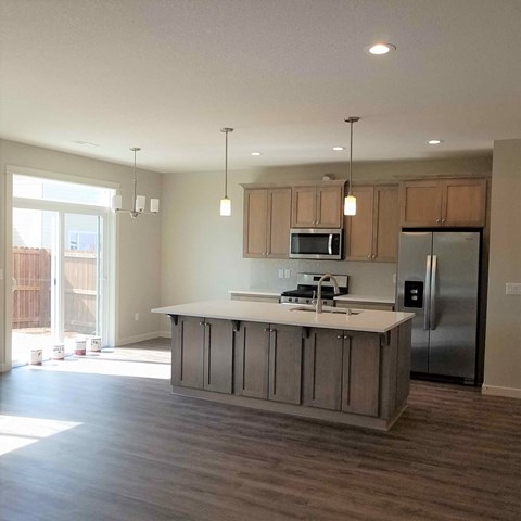 A kitchen with a refrigerator, microwave, and oven.