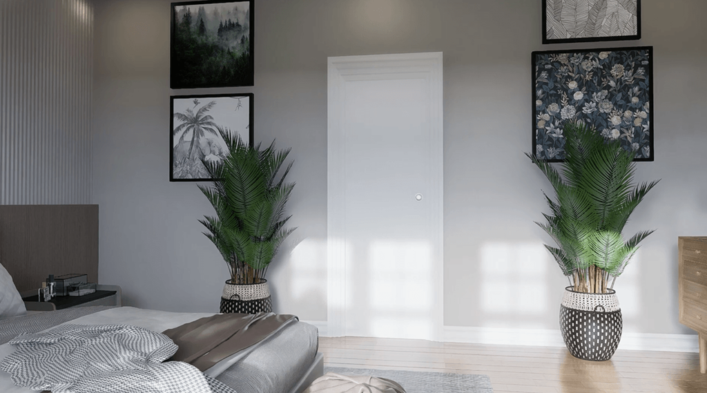 A bedroom with a bed, two potted plants, and pictures on the wall.