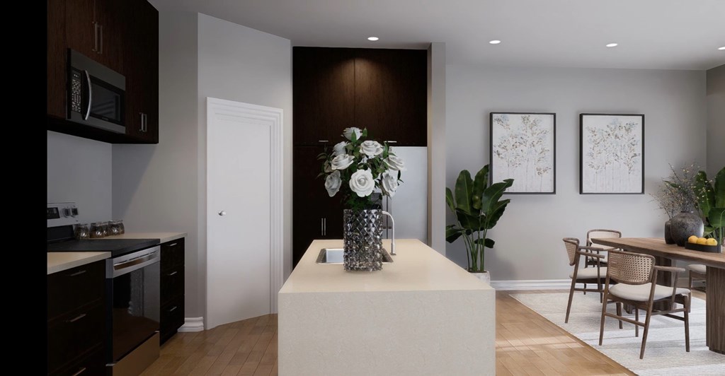 A modern kitchen with dark brown cabinets and a white island with a vase of white flowers on it.