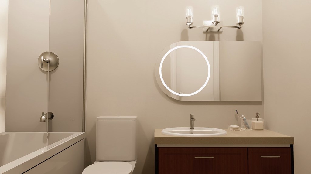 A bathroom with a toilet, sink, and mirror.