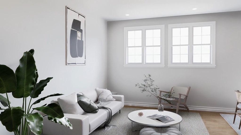 A living room with a white couch, a coffee table, and a plant.