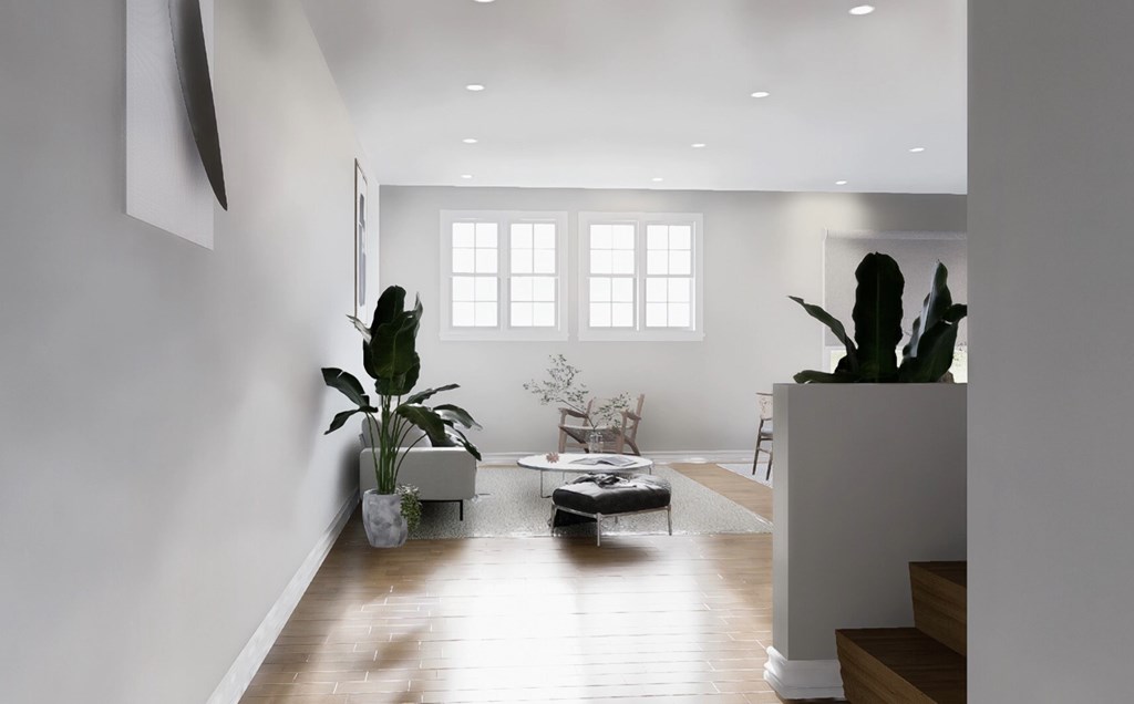 A living room with a couch, a plant, and a painting on the wall.