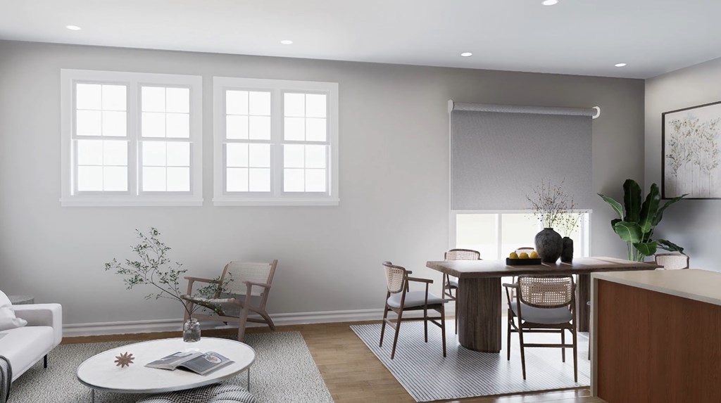 A living room with a white sofa, a coffee table, and a dining table with chairs.