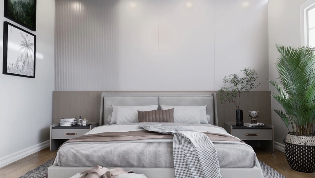 A bedroom with a large bed and a potted plant.