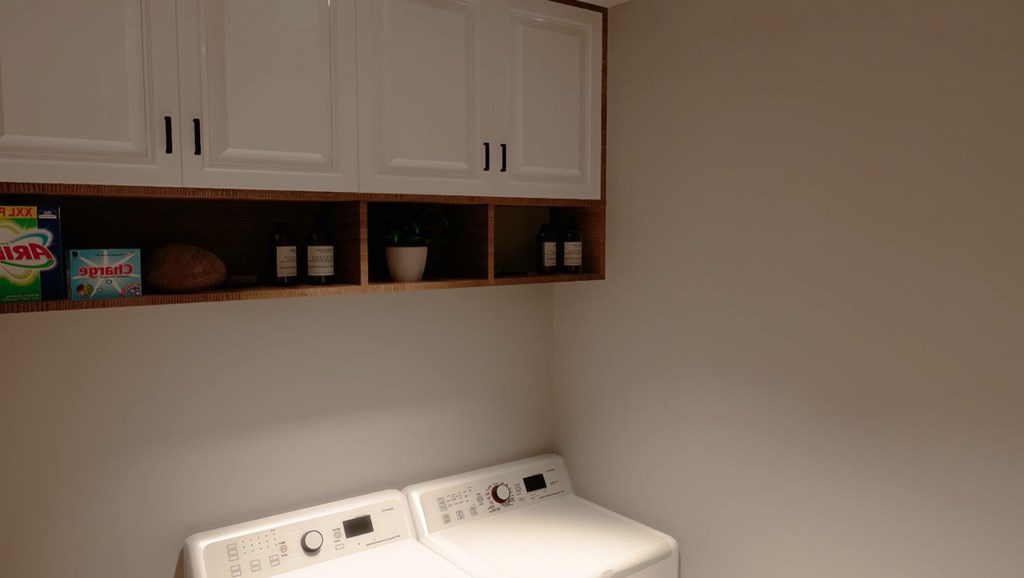 Two white washing machines in front of a wall.