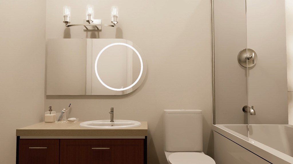 A bathroom with a sink, toilet, and mirror.