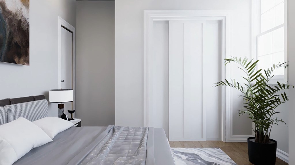 A bedroom with a bed, a lamp, and a plant.