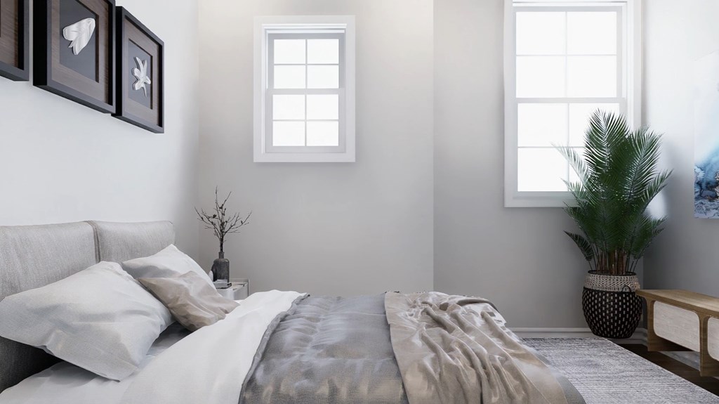 A bedroom with a bed, pillows, a plant, and pictures on the wall.