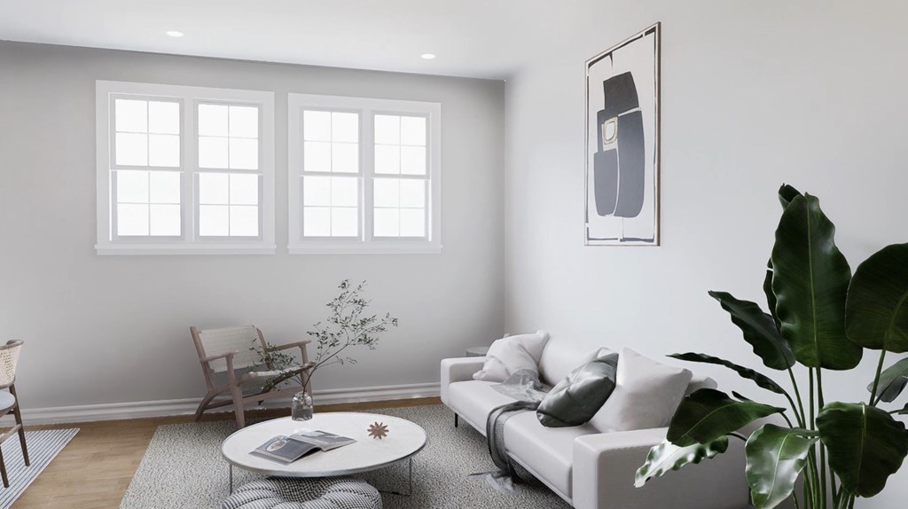 A living room with a white couch, a coffee table, and a plant.