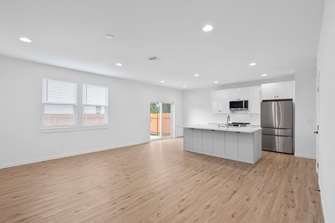 A kitchen with white cabinets and a wooden floor.