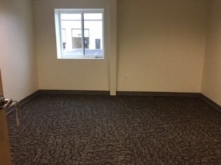 an empty room with a window and a carpeted floor