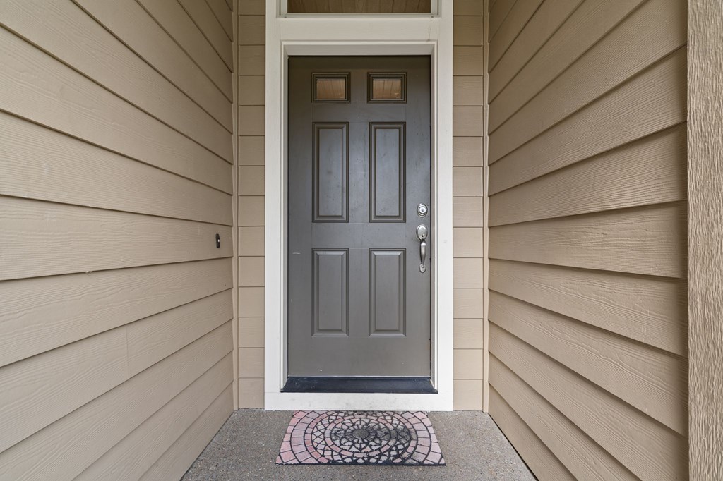 A grey door with a black handle and a doormat in front of it.