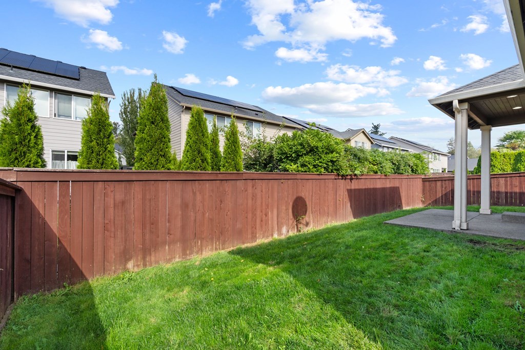 A backyard with a wooden fence and a green lawn.