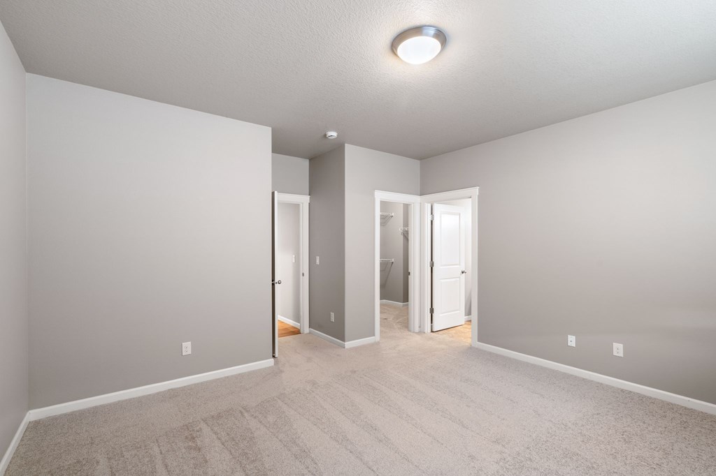 A room with a carpeted floor and three doors.