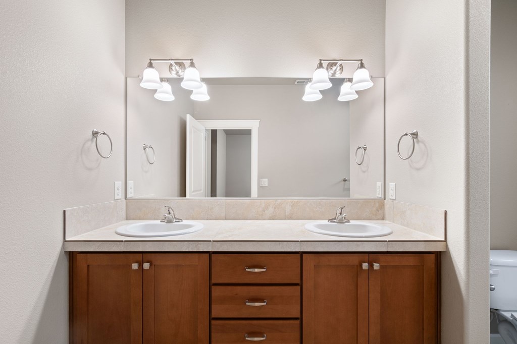 A bathroom with a double sink vanity and a mirror above it.