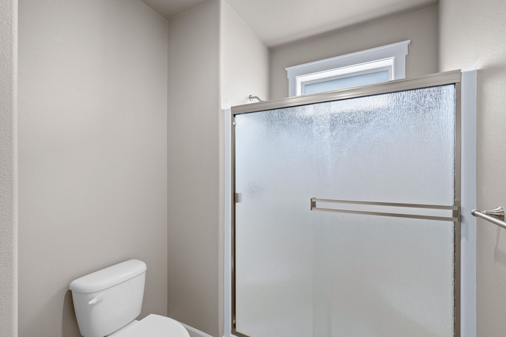 A white toilet sits next to a glass door.