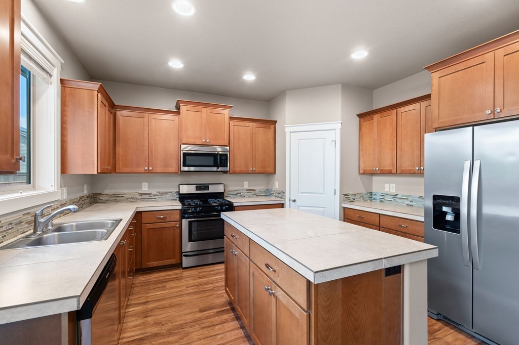 A kitchen with wooden cabinets and a white island.