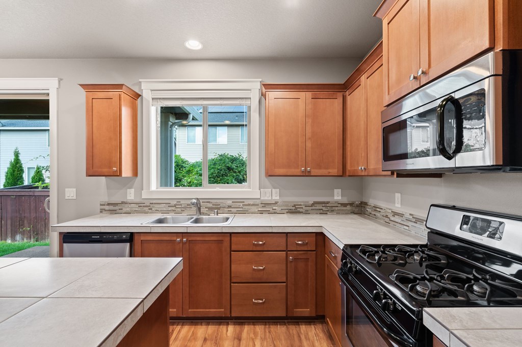 A kitchen with wooden cabinets and a black stove top oven.