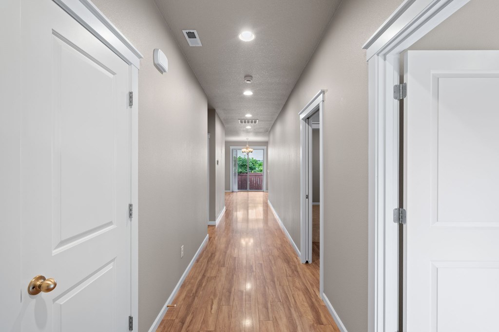A long hallway with white doors on both sides and a light on the ceiling.