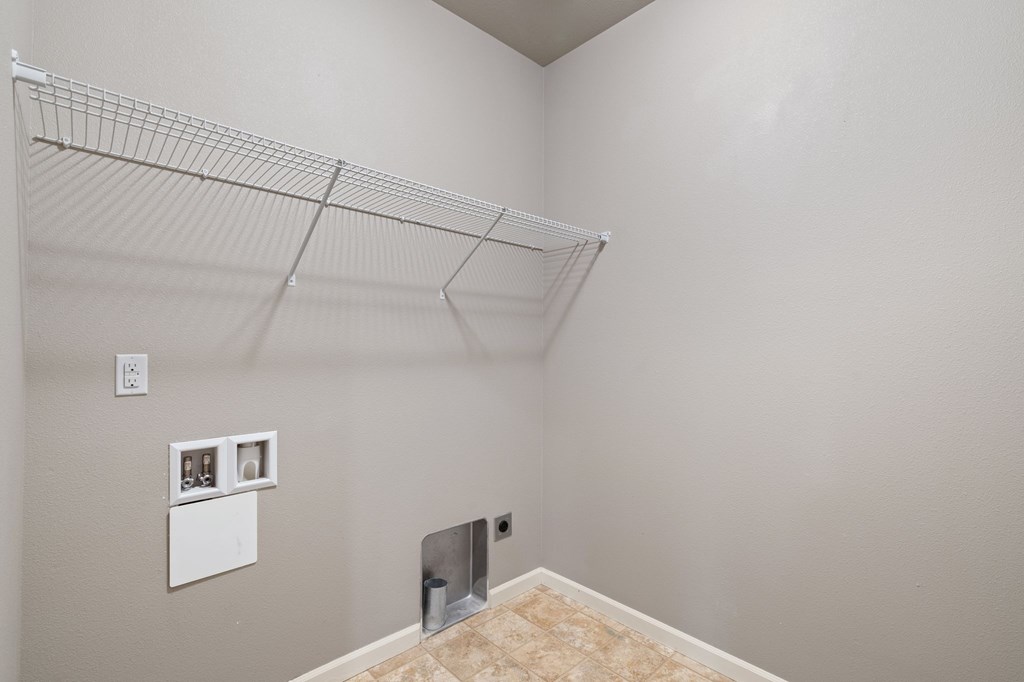 A room with a white wall and a shelf with pictures on it.