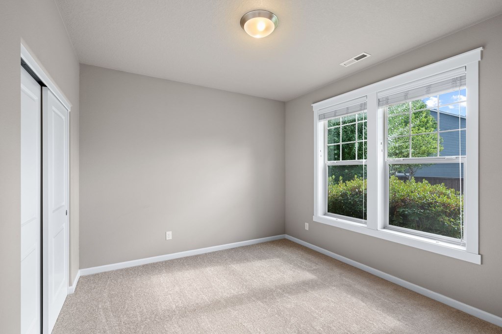A room with a window and a carpeted floor.