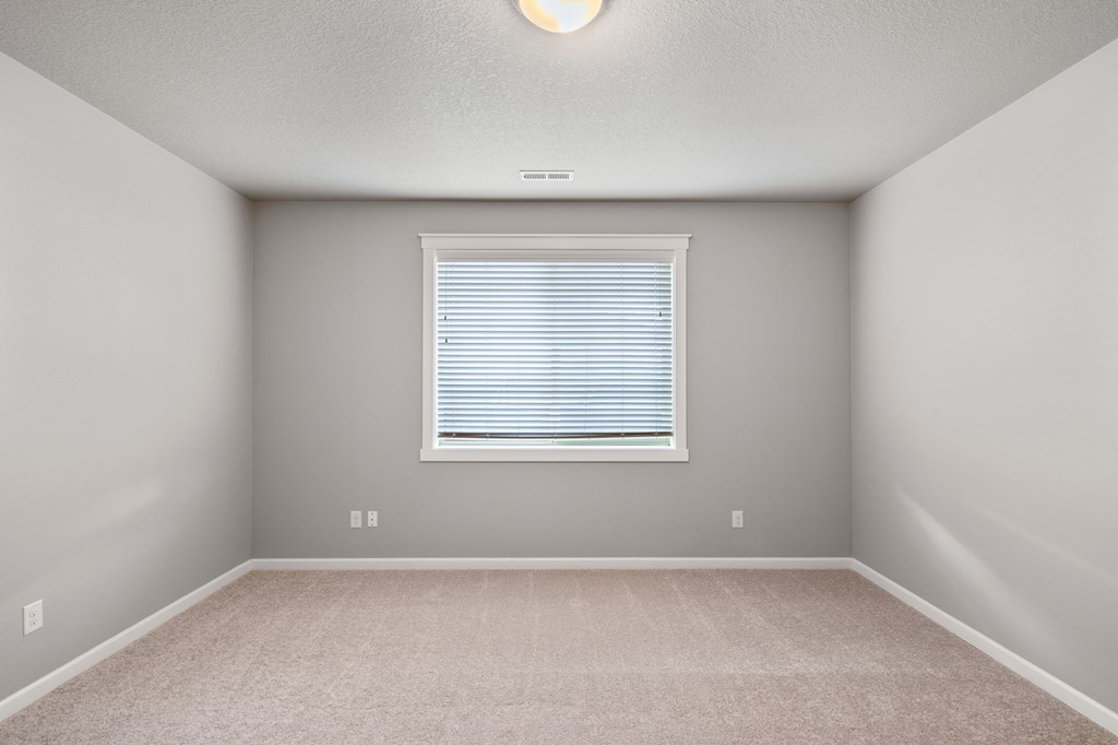 A room with a window and carpeted floor.