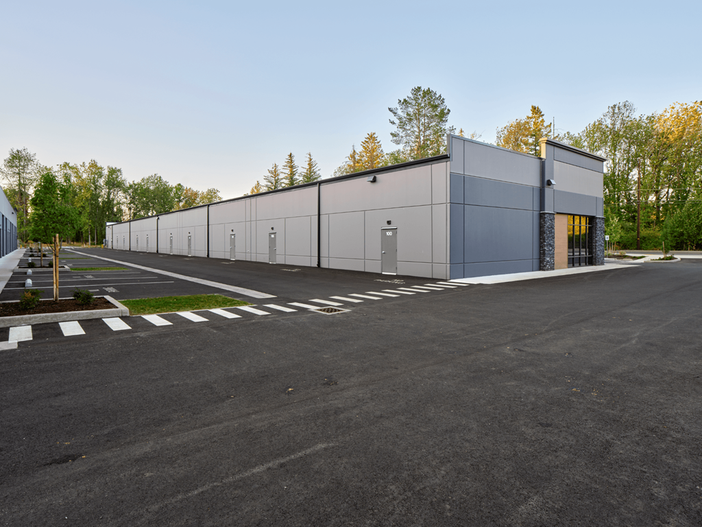 a large industrial building with a parking lot and trees