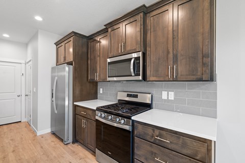A kitchen with wooden cabinets and a stainless steel refrigerator.