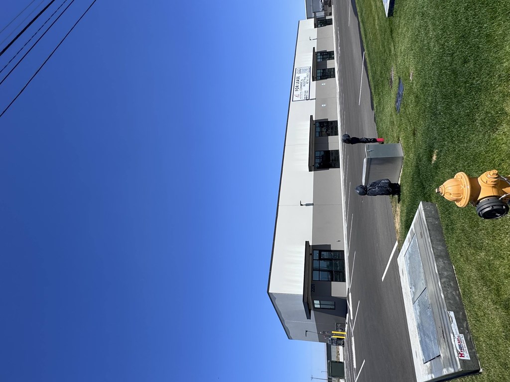 A person in a yellow hat is standing on the grass next to a building.