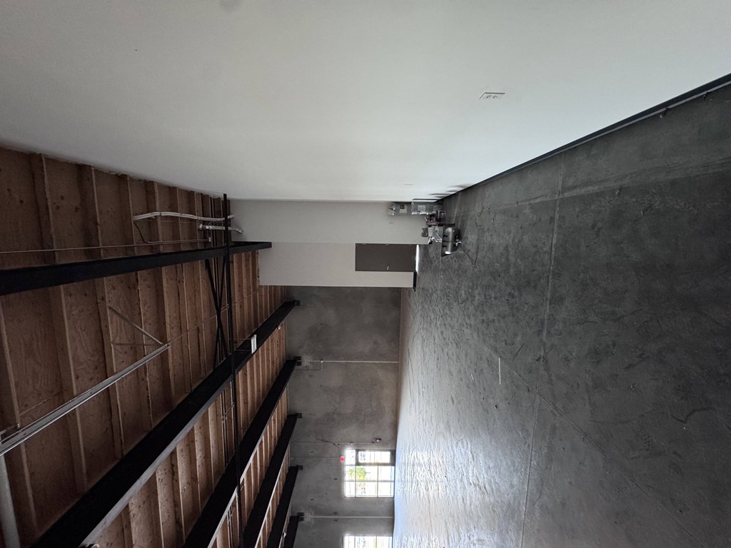 A long hallway with a concrete wall and a window.