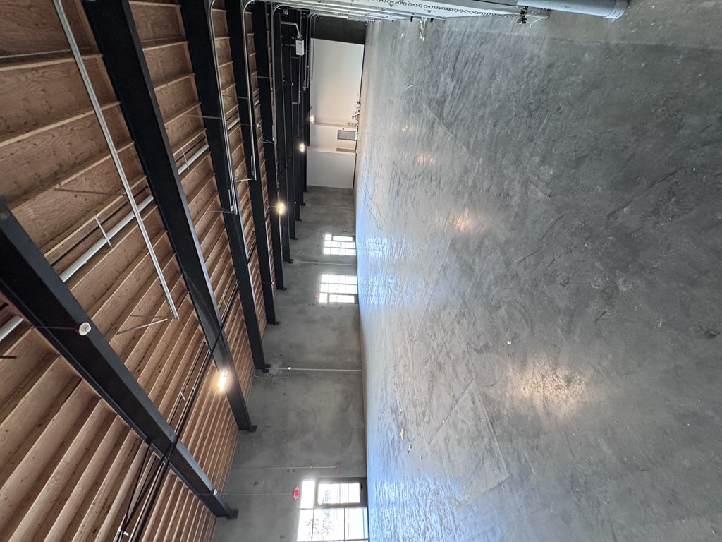 A long hallway with wooden beams on the ceiling and concrete walls.