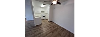a living room and kitchen with wood flooring and a ceiling fan